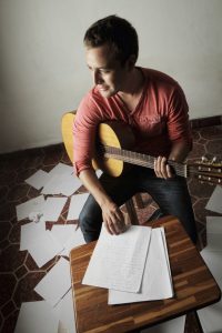 A young man writing songs at home.